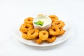 Squid rings fried in batter with white sauce on white plate on white background Royalty Free Stock Photo