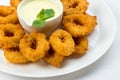 Squid rings fried in batter with white sauce on white plate on white background Royalty Free Stock Photo