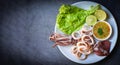 Squid rings on white plate, Fresh squid cooked boiled with lettuce vegetable salad lemon and seafood sauce on black background, Royalty Free Stock Photo