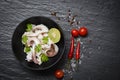 Squid salad bowl with lemon herbs and spices on dark background top view - Tentacles octopus cooked appetizer food hot and spicy Royalty Free Stock Photo