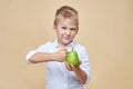 Squinting disheveled little boy beats a green pear