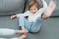 Squirming laughing boy being foot-tickled on the couch.