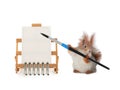 squirrel holds in his paws a brush made of squirrel wool against the background of an easel