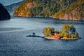 Sramatic summer view with small island with typical Norwegian building with red wall on Lovrafjorden flord