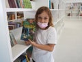 Sremska Mitrovica, Serbia May 15, 2021. A 7-year-old girl wearing a mask and a white T-shirt stands near a bookshelf in