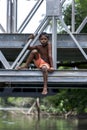 A Sri Lankan boy sits on a steel bridge crossing.