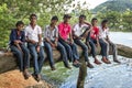 Sri Lankan boys and men sit on a huge tree branch at Kandy in Sri Lanka.