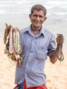 Sri Lankan man sells jewelery to tourists on the white sand beach