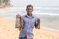 Sri Lankan man sells jewelery to tourists on the white sand beach