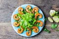 Srimp lettuce salad on blue plate, wooden rustic background Royalty Free Stock Photo