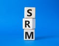 SRM - Sustainability Risk Management symbol. Wooden cubes with word SRM. Beautiful blue background. Business and Finace and SRM