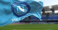 SSC Napoli flag waving with the Diego Armando Maradona Stadium blurred in the background