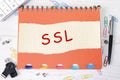 SSL word is written on a sheet in a cage lying on a notebook on the table next to stationery