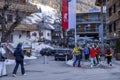 People in ski wear walks through street beside chalet at winter resort