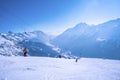 Skiers walking on snowy mountain slope at winter resort on sunny day