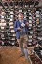 Happy male owner showing wine bottle while standing in modern wine store