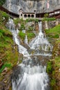 St. Beatus Cave and waterfalls above Thunersee, Sundlauenen, Switzerland. Falls are running down the mountain with a green grass