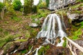 St. Beatus Cave and waterfalls above Thunersee, Sundlauenen, Switzerland. Falls are running down the mountain with a green grass