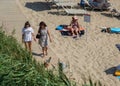 St Constantine and Elena resort, Varna, Bulgaria 08/24/2019 - Two females walking small dog at the beach, summertime relaxing