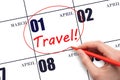 Hand drawing a red circle and writing the text TRAVEL on the calendar date April 1. Travel planning.