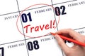 Hand drawing a red circle and writing the text TRAVEL on the calendar date 1 February. Travel planning.