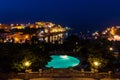 St. George`s Bay seafront lights by night, a blue swimming pool, boats, yachts anchored. St Julian`s, Paceville, Malta.