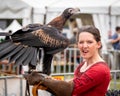 Captive wedge tailed eagle with female trainer / handler in red dress looking at camera getting ready for flight exhibition at a