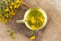 St. John's wort tea is a therapeutic healthy drink A cup on a wooden background A bouquet of St. John's wort on Royalty Free Stock Photo