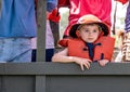 Young boy wearing life jacket stands on a boat deck