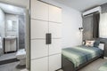 St Julians, Malta - April 28th 2020: Small twin bedroom with turqoise green bedding and a tiny grey ensuite bathroom