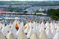 21st June 2015. Glastonbury Festival, UK. Smoky, evening backlight as people walk through the festival with the pyramid stage in t