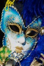 Close up of typical Venetian carnival masks with bright blue feathers.