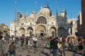 Tourists feed pigeons make photos with Saint Mark Basilica at the background at Piazza San Marco in Venice, Italy.