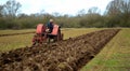 Vintage red International 1930`s tractor ploughing field. Royalty Free Stock Photo