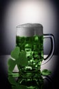 St. Patrick Day concept. Glass of green beer with foam on black background with shamrock. Royalty Free Stock Photo