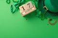Top view of the date on a wooden calendar, leprechaun\'s hat, lucky horseshoe, trefoils, confetti on green background