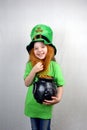 St. Patrick\'s Day. Charming seven years old girl laugh and showing off gold coin with four-petal lucky clover leaf Royalty Free Stock Photo