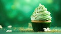 St. Patrick's Day cupcake with whipped cream decorated clover on green background.