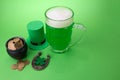 St Patrick`s Day green beer with shamrock, pot with gold coins, horseshoe and Leprechaun hat against green background. Royalty Free Stock Photo