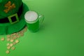 St Patrick`s Day green beer with shamrock, pot with gold coins, horseshoe and Leprechaun hat against green background. Royalty Free Stock Photo