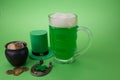 St Patrick`s Day green beer with shamrock, pot with gold coins, horseshoe and Leprechaun hat against green background.