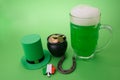 St Patrick`s Day green beer with shamrock, pot with gold coins, horseshoe and Leprechaun hat against green background.