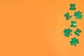 St. Patrick`s Day low border paper shamrocks and leprechaun hats on orange background. Royalty Free Stock Photo