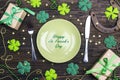 St.Patrick`s day table setting with cutlery and lucky symbols on wooden table.