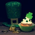 St. Patricks Day Cupcake decorated with Shamrocks and gold coins, and top hat on Dark Rustic Wood Table and Background with copy s Royalty Free Stock Photo