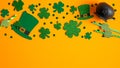 St Patricks Day frame border of shamrock and four-leaf clovers, Irish elf hats, pot of gold on orange background. Banner design, Royalty Free Stock Photo