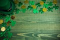 St Patricks Day frame of shamrocks, gold coins and leprechaun hat on green wood