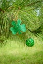 St Patricks Day glitter shamrock and green ornament hanging in a pine tree