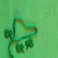 St. Patricks Day or Irish Green Ribbon Heart on Burlap Linen Background with shamrocks and copy space. It`s square with a trendy