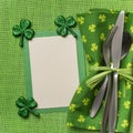 St. Patricks Day or Irish Table Place Setting with a Menu card. It has a green napkin with silverware on a tablecloth with copy s